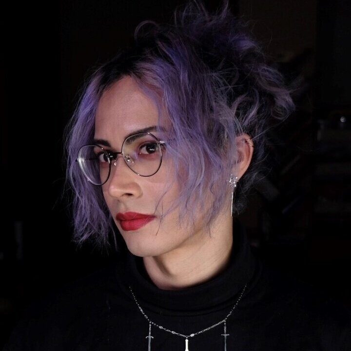 Vileru Trivexi - pitch black background, she's turned the right revealing the left side of her face, thin glasses, smart muted pleasant grimace, red lip stick, purple hair, wavy falling onto her face;;