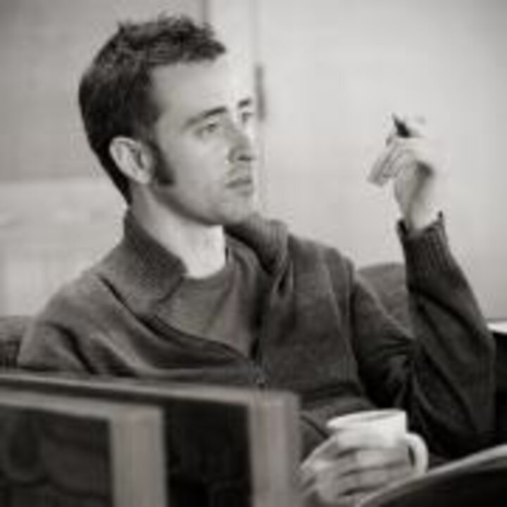 dr Adam R Thompson - in chair asking question at a conference black and white ; hand raised with pen in it